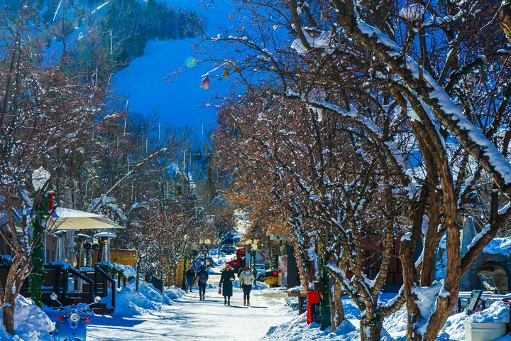 A snowy street in Aspen lined with low brick buildings and mountains behind