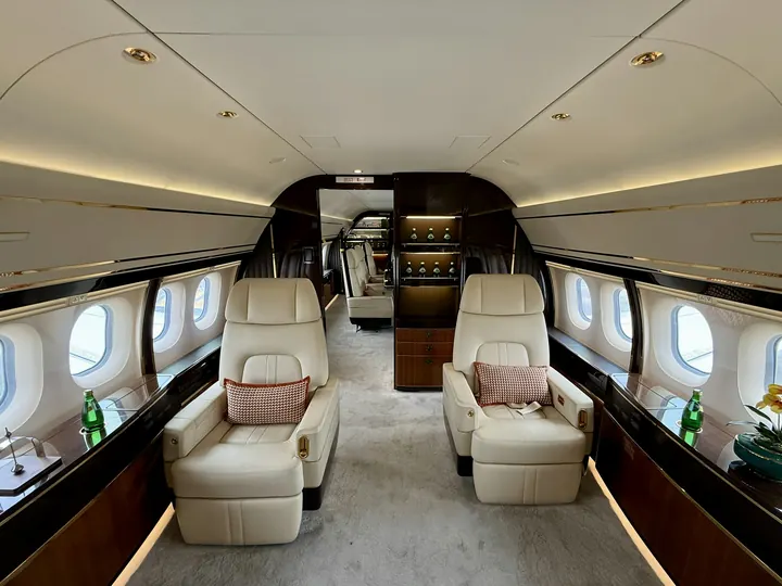 A long cabin with armchairs, a divan and a galley beyond