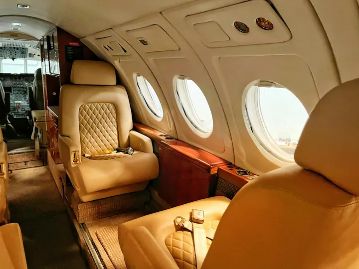 Quilted tan leather seats beside oval windows in a midsize jet