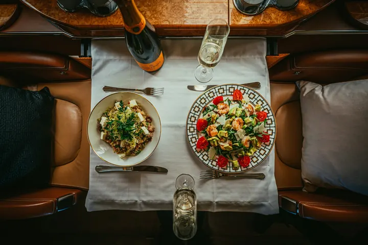 A shared meal of salads and wine laid out on a cabin table, seen from above