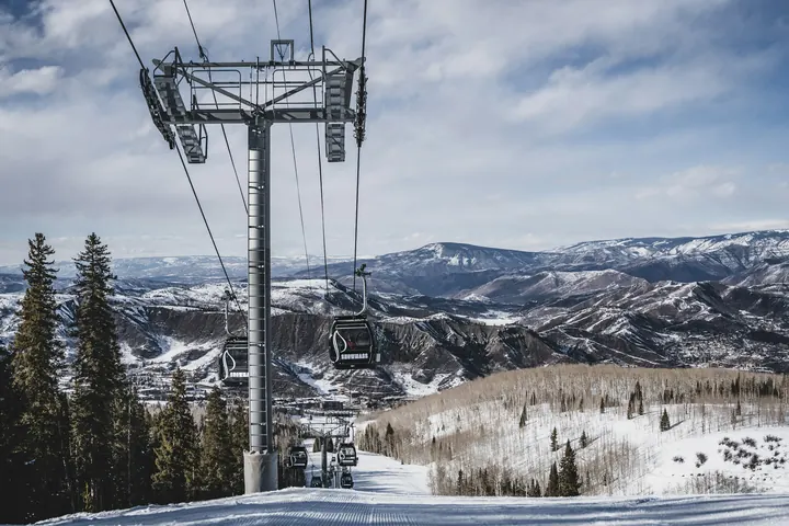Gondola cabins rising over snowy slopes above Aspen