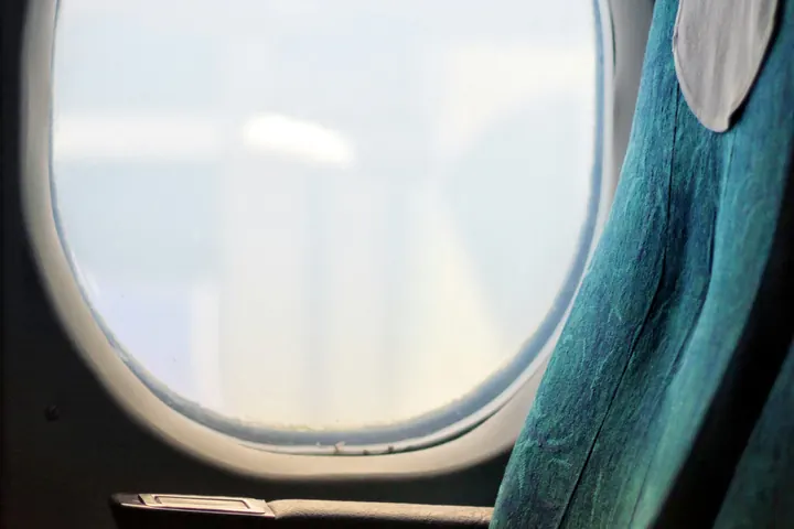 A single leather seat beside an aircraft window in soft evening light