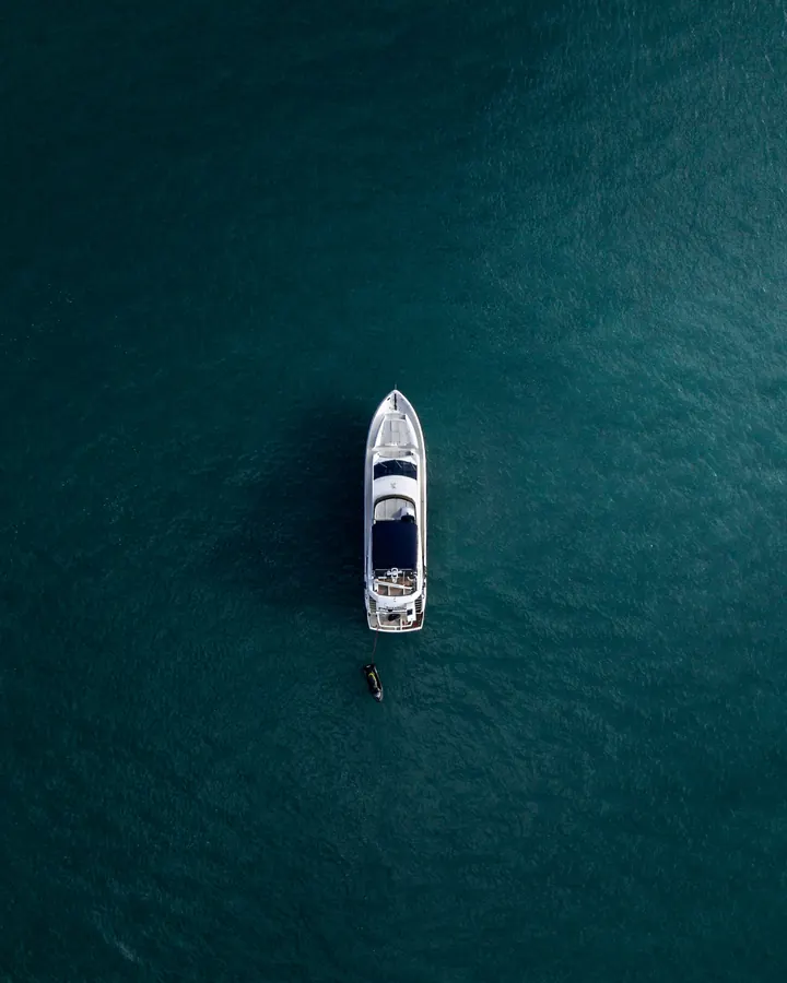 A white yacht crossing deep blue water, seen from directly above